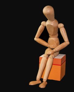 wooden figure sitting holding stomach